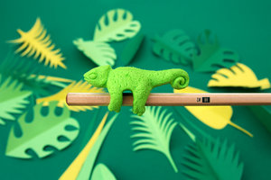 Side view of chameleon eraser with paper leaves in the background