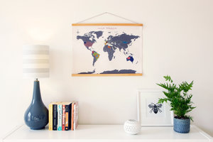 cross stitch map on a living room wall with books and a lamp