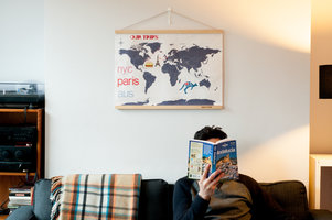 cross stitch map of the world above man reading book