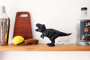 t-rex dinosaur bottle opener on shelf with gin and lemon
