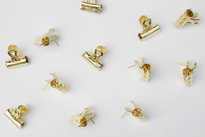 gold push pin clips on a grey background