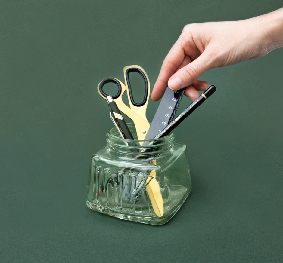 Hand taking ruler from ink pen pot