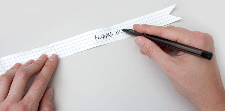 Writing happy birthday message on ribbon