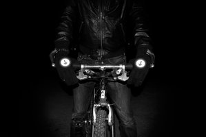 Man holding bicycle handle bars wearing reflective biker gloves