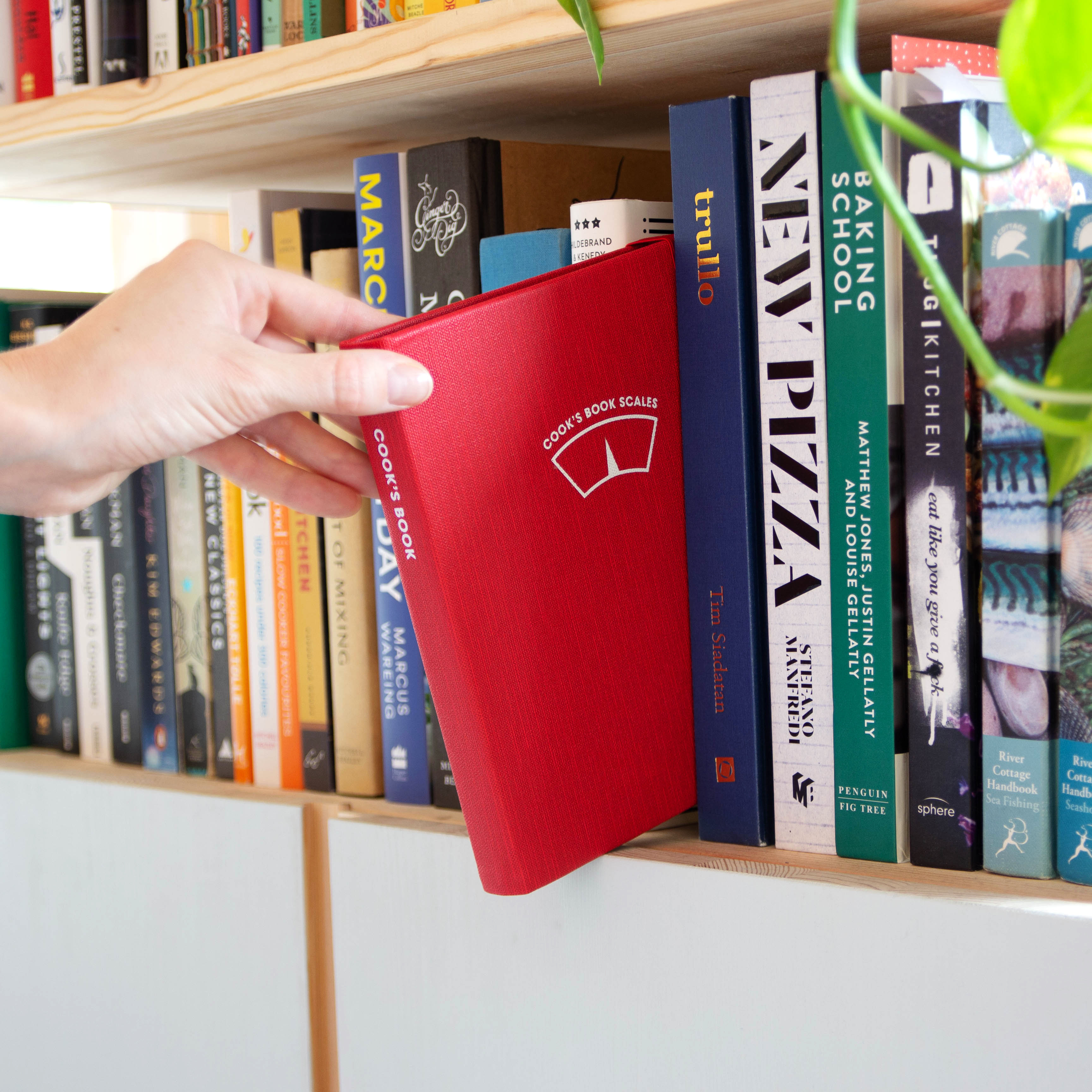 Hand taking cooks book scales from bookshelf