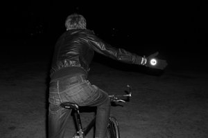 Man riding a bike and indicating wearing reflective cycling gloves