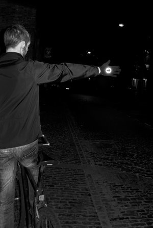 Man indicating at night wearing highly reflective bike gloves