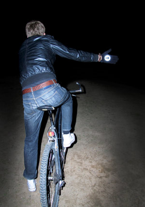 Man riding a bike and indicating wearing reflective cycling gloves