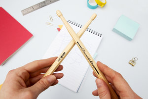 Wooden drumstick pens crossed over in hands