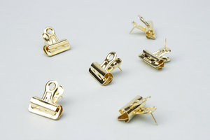 gold push pin clips on a grey background