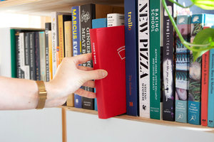 Hand taking cook's book scales from bookshelf
