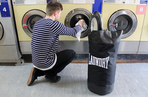 putting clothes from laundry boxing bag into washer