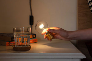 cordless light bulb night light being lifted from bedside table