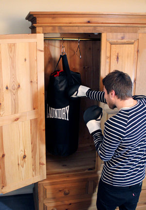 man punching punch bag hidden in wardrobe
