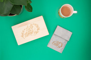 Wooden box and phone signal blocking bag on a green background with a cup of tea