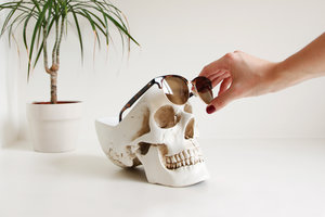 woman removing sunglasses from skull desk organizer