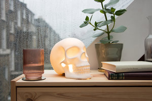 Skull table lamp on bedside table with rain on the window